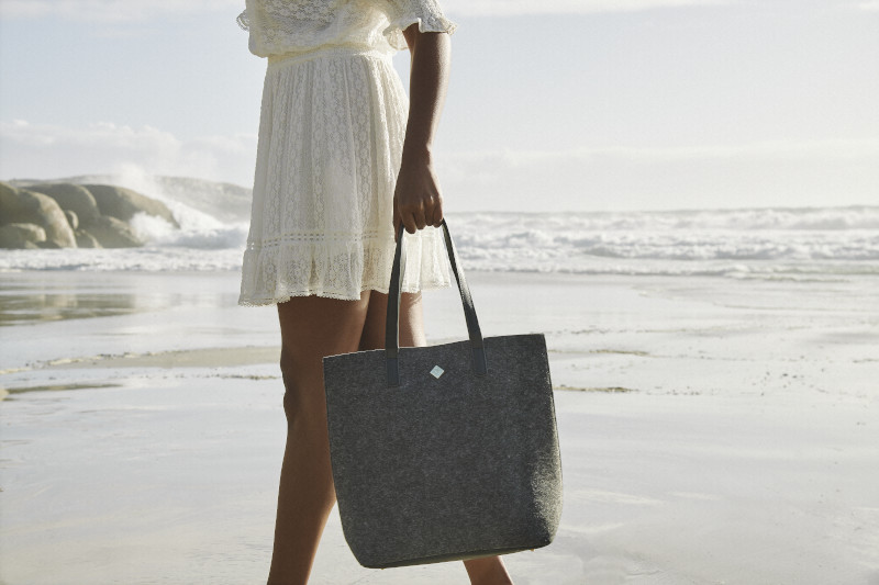picture of a woman walking at the beach with a handbag