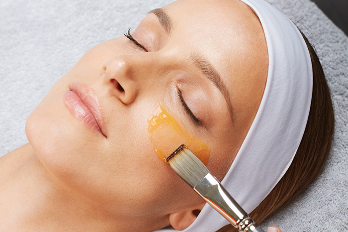 Woman receiving under eye treatment with a brush and serum