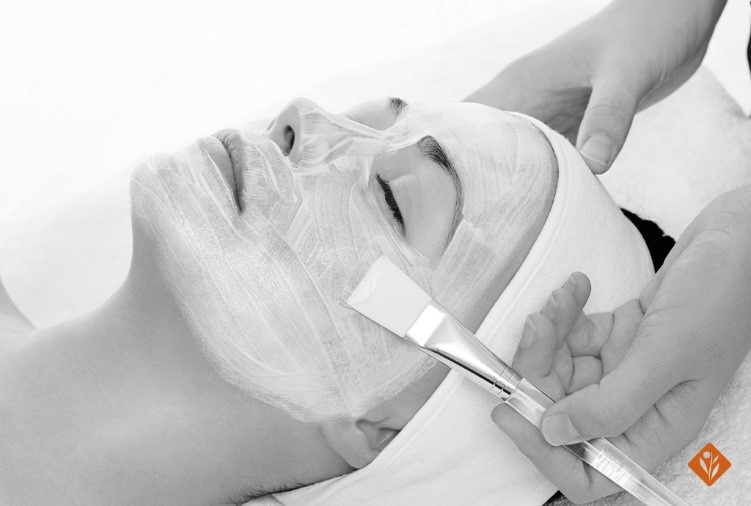 Black and white, woman getting a facial done with a brush